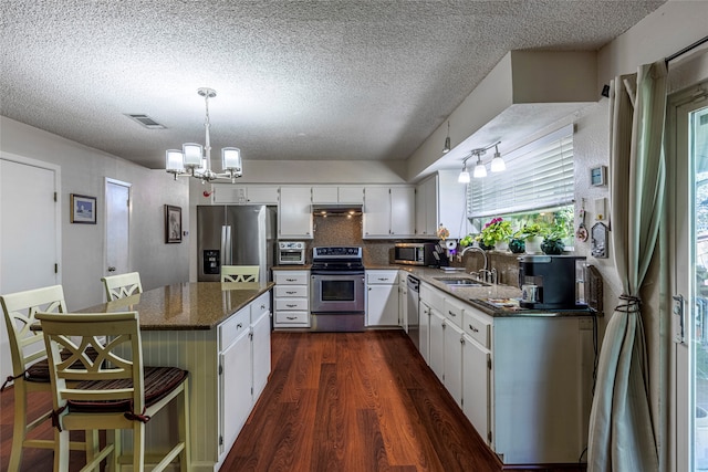 kitchen with sink, stainless steel appliances, dark hardwood / wood-style flooring, dark stone countertops, and white cabinets