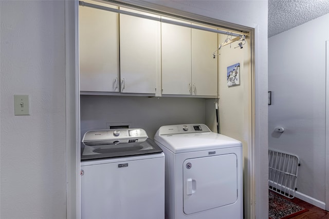 laundry area with cabinets, wood-type flooring, a textured ceiling, and separate washer and dryer