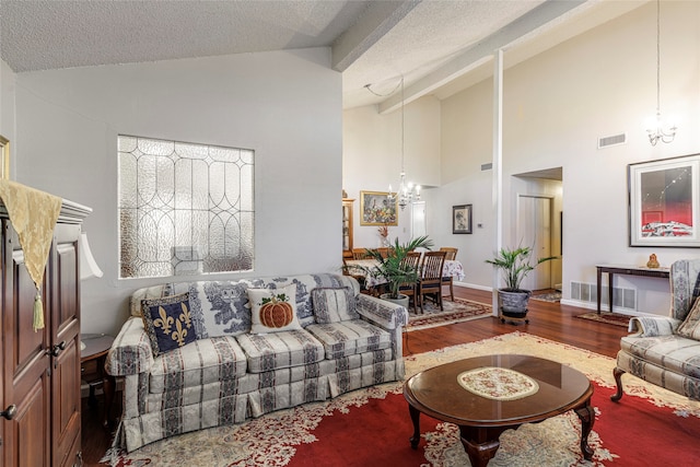 living room featuring hardwood / wood-style floors, a textured ceiling, high vaulted ceiling, and a chandelier