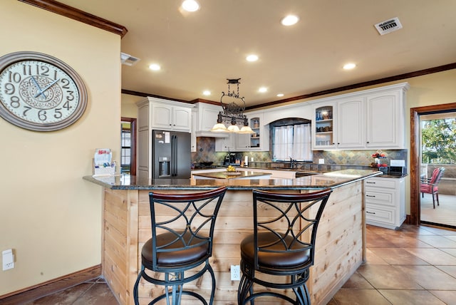 kitchen with pendant lighting, dark stone counters, black appliances, white cabinets, and kitchen peninsula