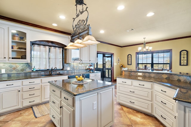 kitchen with a center island, decorative light fixtures, backsplash, and sink