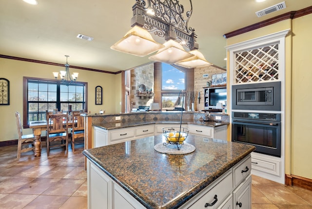 kitchen with white cabinetry, crown molding, a kitchen island, and stainless steel appliances