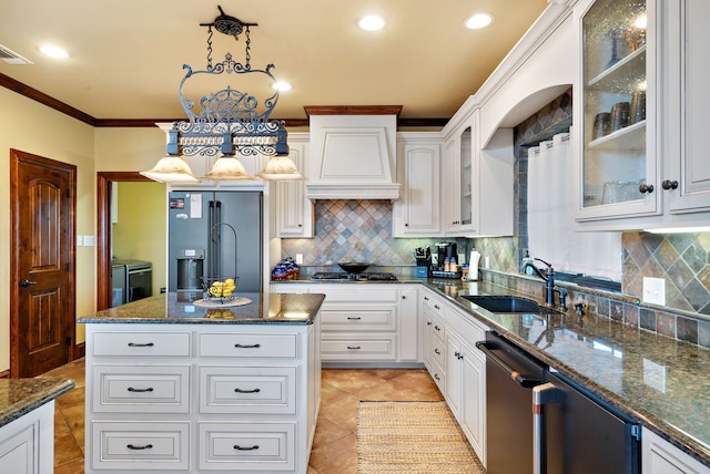 kitchen with pendant lighting, sink, appliances with stainless steel finishes, a kitchen island, and white cabinetry