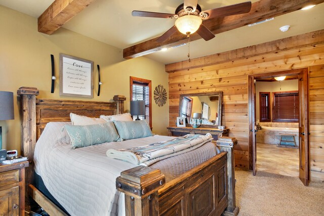 bedroom with ceiling fan, beam ceiling, light colored carpet, and wooden walls