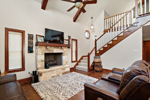 living room featuring a stone fireplace, ceiling fan, high vaulted ceiling, and dark wood-type flooring