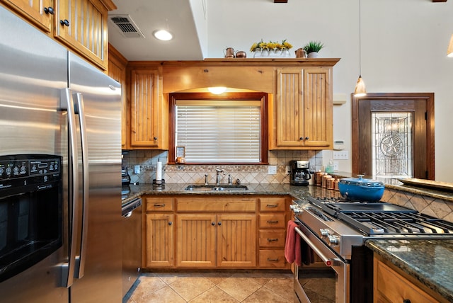 kitchen with sink, stainless steel appliances, tasteful backsplash, pendant lighting, and dark stone counters