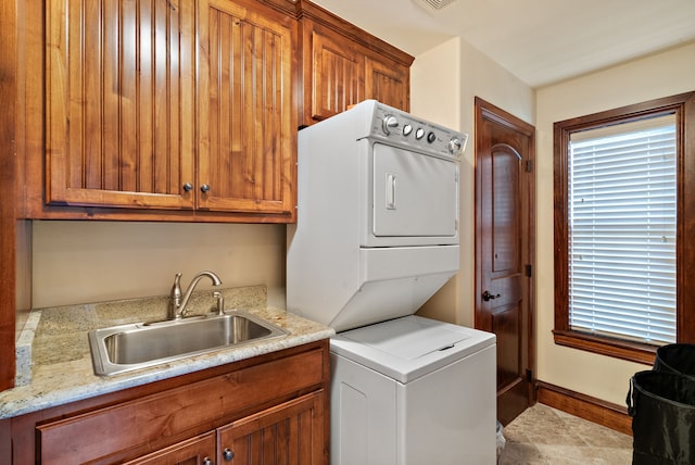 washroom featuring stacked washer / dryer, sink, and cabinets