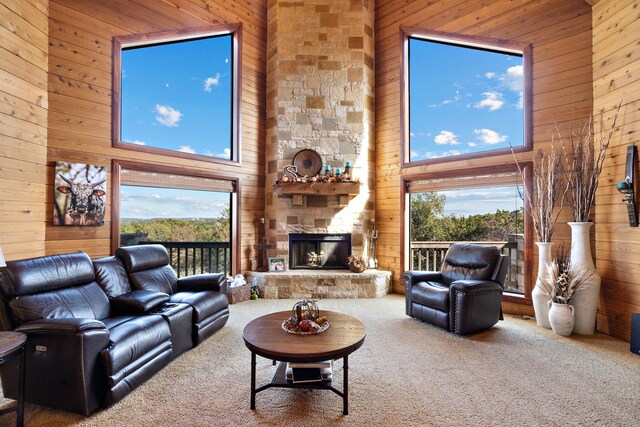 carpeted living room with wood walls, a fireplace, and a towering ceiling