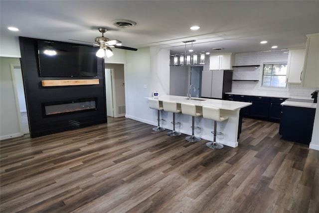 kitchen with dark wood-type flooring, sink, pendant lighting, white cabinetry, and a breakfast bar area