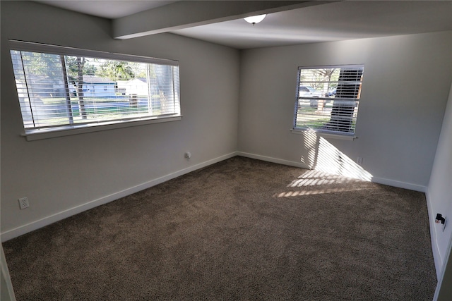 unfurnished room with beam ceiling and dark carpet