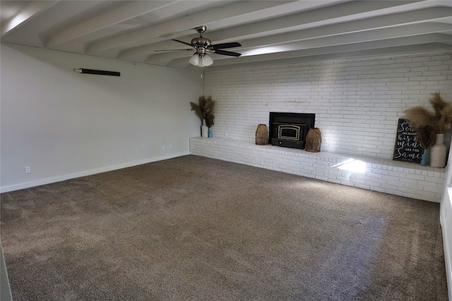 unfurnished living room with carpet floors, a wood stove, ceiling fan, and beamed ceiling