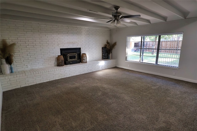 unfurnished living room featuring carpet, a wood stove, ceiling fan, and beamed ceiling