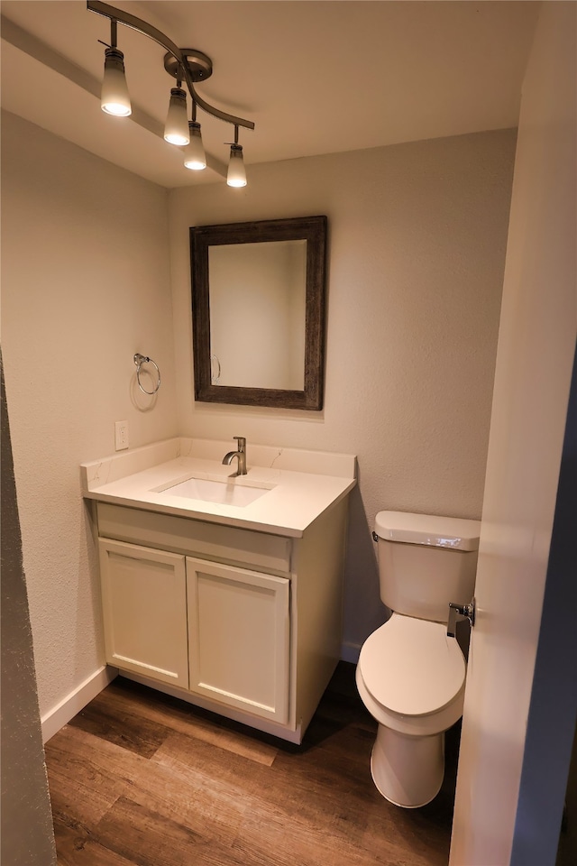 bathroom featuring toilet, vanity, and hardwood / wood-style flooring