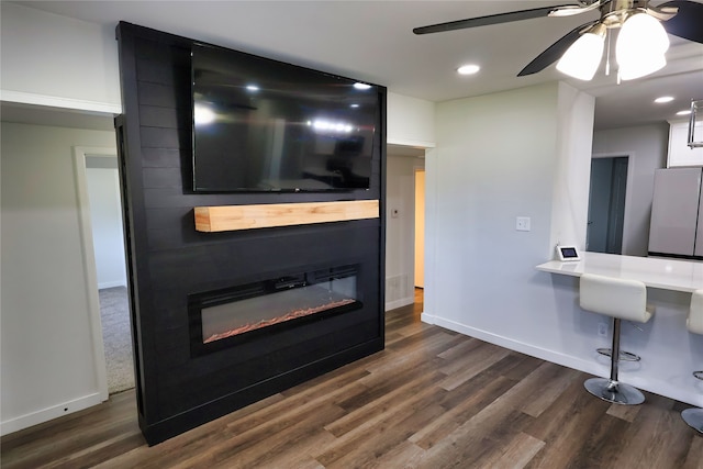 living room with dark hardwood / wood-style flooring, ceiling fan, and a fireplace