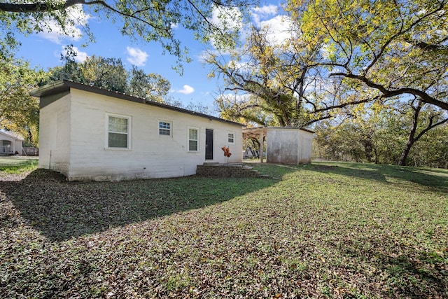 rear view of house with a shed and a lawn