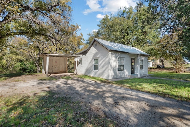 view of front of home with a storage shed and a front lawn