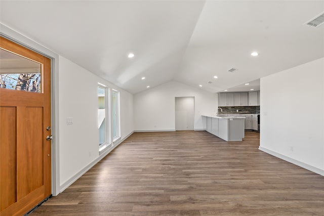 unfurnished living room featuring hardwood / wood-style floors, lofted ceiling, and sink