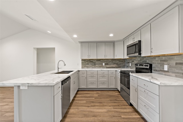 kitchen featuring sink, vaulted ceiling, light wood-type flooring, kitchen peninsula, and stainless steel appliances