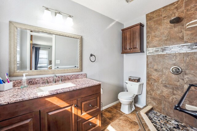 bathroom with a tile shower, tile patterned floors, vanity, and toilet