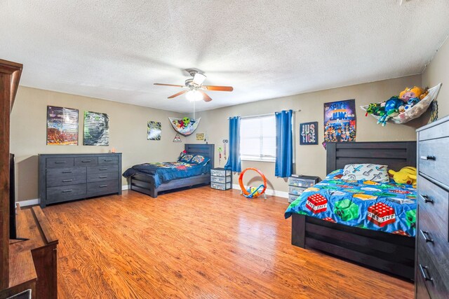 bedroom featuring hardwood / wood-style floors, ceiling fan, and a textured ceiling