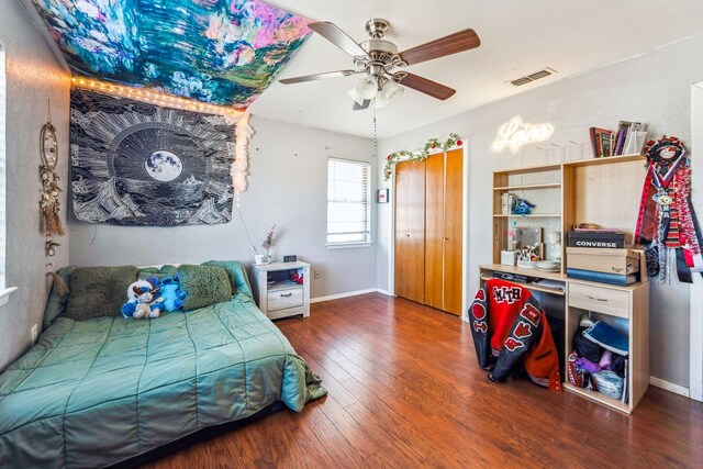 bedroom with dark hardwood / wood-style floors, ceiling fan, and a closet