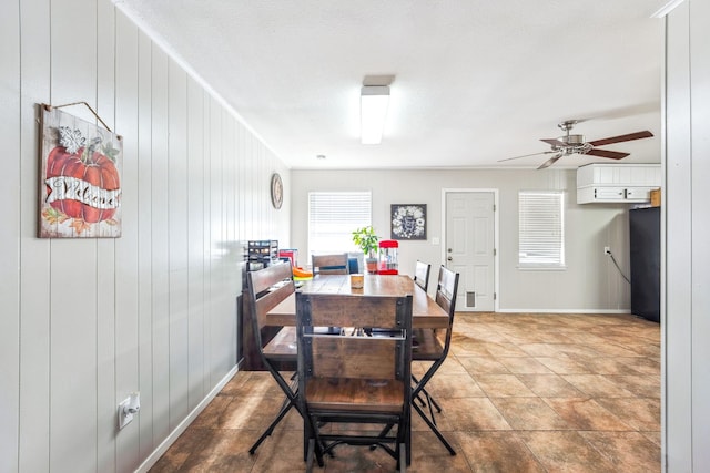 dining area with ceiling fan and wooden walls