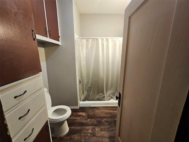 bathroom with hardwood / wood-style floors, a shower with curtain, and toilet