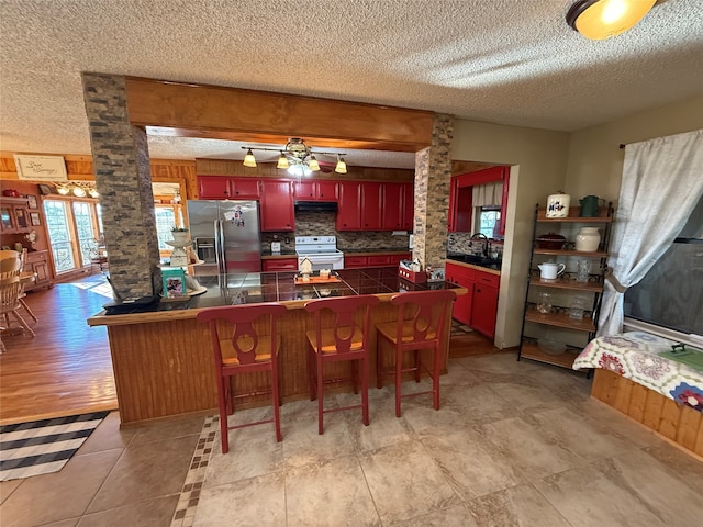 kitchen with backsplash, white electric stove, light hardwood / wood-style flooring, stainless steel fridge, and kitchen peninsula