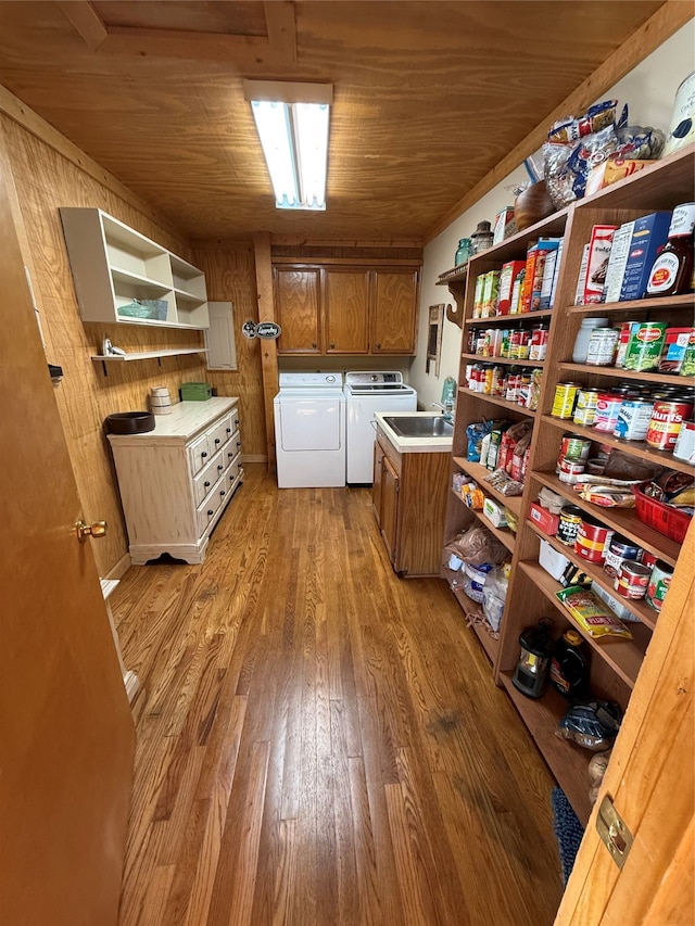 clothes washing area featuring washing machine and clothes dryer, cabinets, wood walls, wood ceiling, and hardwood / wood-style flooring