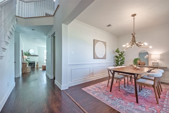 dining area with a towering ceiling, an inviting chandelier, crown molding, and dark wood-type flooring