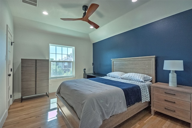 bedroom featuring light hardwood / wood-style floors, vaulted ceiling, and ceiling fan