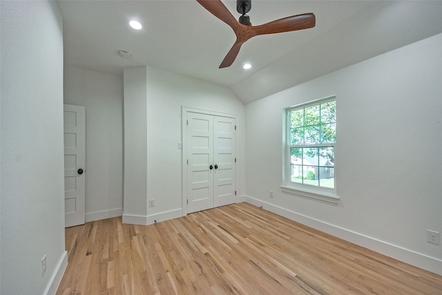 unfurnished bedroom featuring ceiling fan, a closet, light wood-type flooring, and lofted ceiling