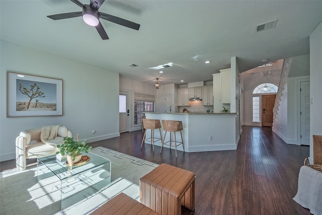 living room with ceiling fan and dark wood-type flooring