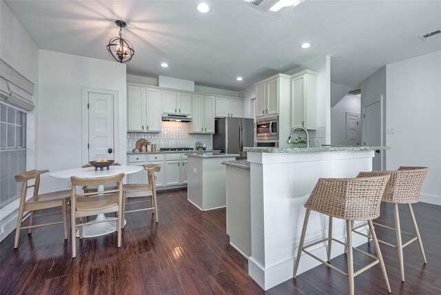 kitchen featuring white cabinets, dark hardwood / wood-style floors, decorative backsplash, appliances with stainless steel finishes, and decorative light fixtures