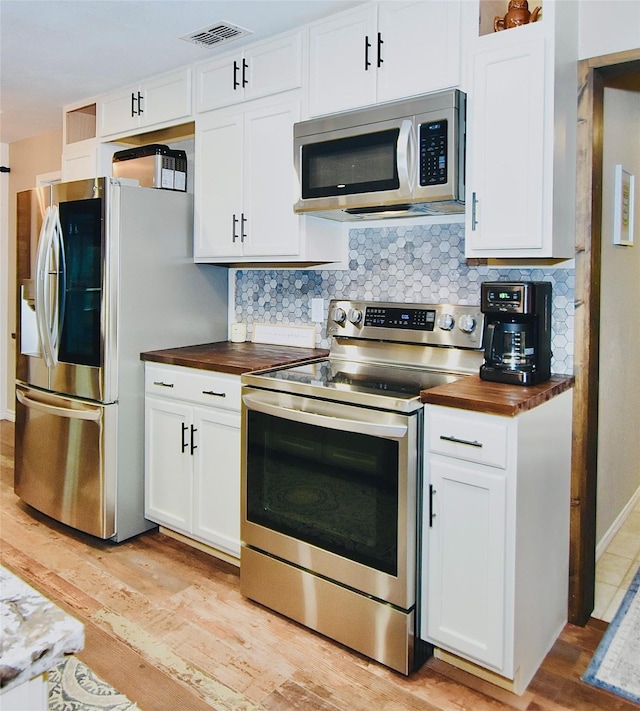 kitchen with appliances with stainless steel finishes, light hardwood / wood-style floors, white cabinetry, and butcher block counters