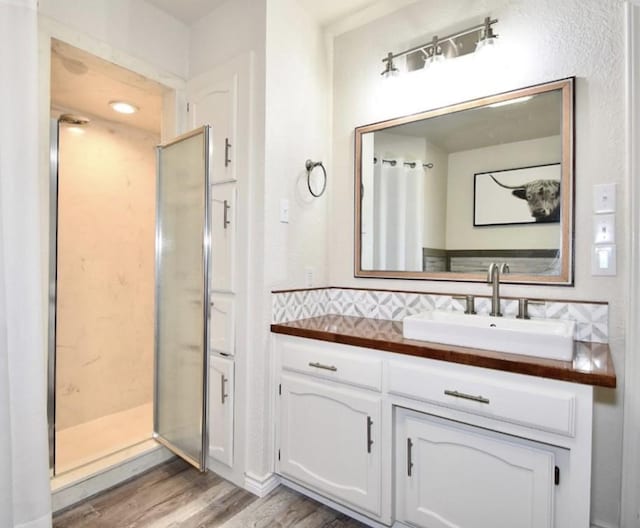 bathroom with backsplash, vanity, a shower with shower door, and hardwood / wood-style flooring