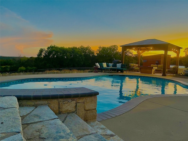 pool at dusk featuring a gazebo, outdoor lounge area, and a patio