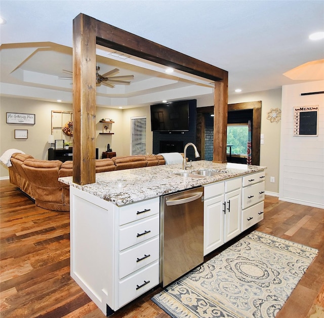 kitchen with dishwasher, sink, a tray ceiling, light stone counters, and white cabinetry