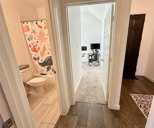 bathroom with shower / bath combo, hardwood / wood-style flooring, toilet, and lofted ceiling