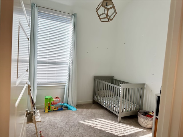 bedroom with multiple windows, light carpet, and a crib