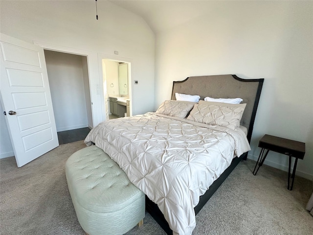 bedroom with vaulted ceiling, carpet floors, and ensuite bath