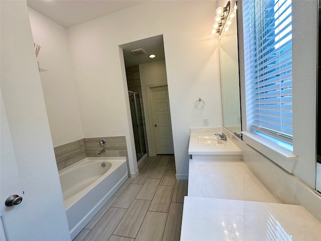 bathroom with shower with separate bathtub and vanity