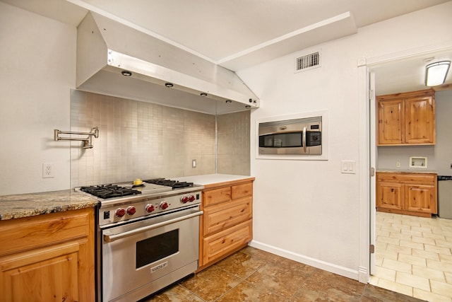 kitchen with appliances with stainless steel finishes, light stone counters, and decorative backsplash