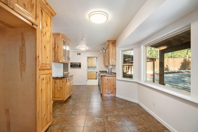 kitchen with dark stone countertops and light brown cabinetry