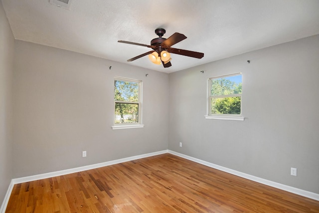 spare room featuring plenty of natural light, hardwood / wood-style floors, and ceiling fan