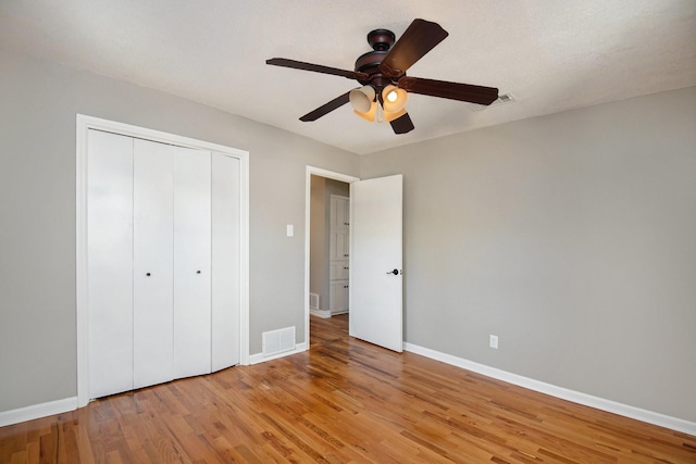 unfurnished bedroom with ceiling fan, a closet, and light wood-type flooring