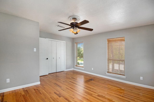 unfurnished bedroom with ceiling fan, a closet, light hardwood / wood-style flooring, and a textured ceiling