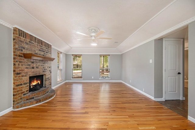 unfurnished living room featuring crown molding, a brick fireplace, ceiling fan, and light hardwood / wood-style floors