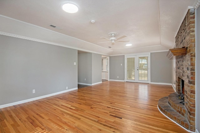 unfurnished living room with a fireplace, french doors, ceiling fan, and light wood-type flooring