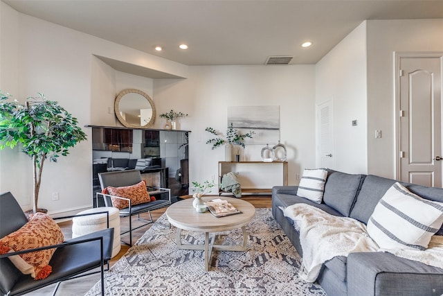 living room featuring a tiled fireplace and wood-type flooring